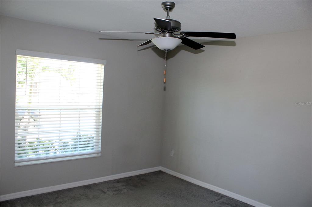 A bedroom with gray walls, gray carpeting, a window with blinds, and a ceiling fan — 17152 SUNSHINE MIMOSA STREET, WIMAUMA, FL