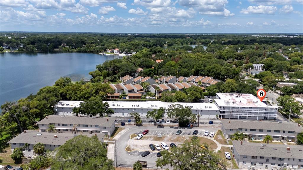 An aerial view shows multiple apartment buildings situated near a lake with a parking lot — 320 LAKEVIEW STREET UNIT 323, ORLANDO, FL