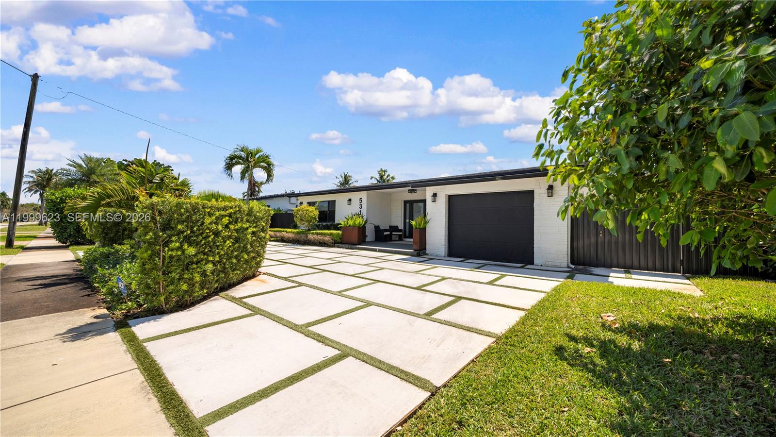 A single-story house features a white brick exterior, a dark garage door, and a paved driveway — 5316 Jackson St, Hollywood FL 33021, HOLLYWOOD, FL