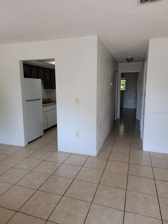 A view of a tiled room leading to a kitchen and a hallway — 1216 KENNEDY ROAD UNIT 8, DAYTONA BEACH, FL