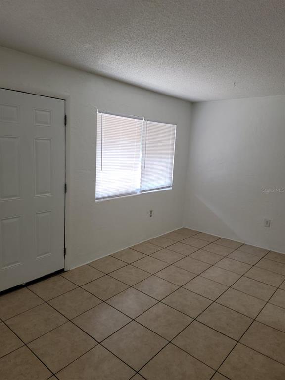 A room with white walls, a white door, a window with blinds, and tiled flooring — 1216 KENNEDY ROAD UNIT 8, DAYTONA BEACH, FL