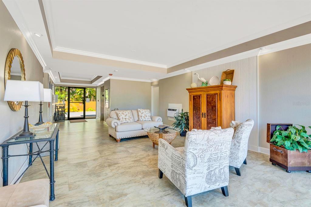 A furnished lobby features tile flooring, a beige sofa, patterned armchairs, and a wooden cabinet — 350 S POLK DRIVE UNIT 302, SARASOTA, FL