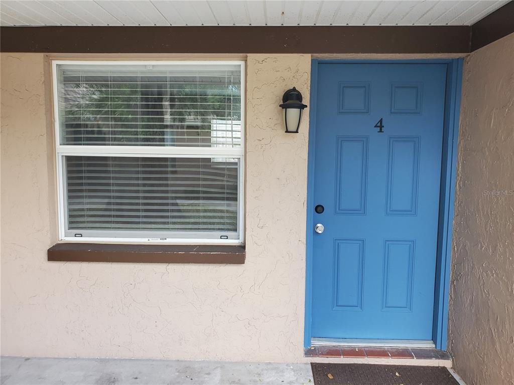 A blue front door with the number four and a window with blinds on stucco — 107 W CLAY AVENUE UNIT 4, BRANDON, FL