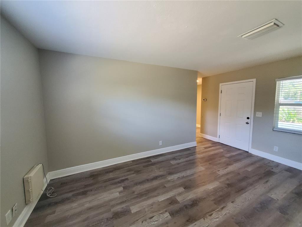 An empty room features gray walls, wood-look flooring, a white door, and a window — 107 W CLAY AVENUE UNIT 4, BRANDON, FL
