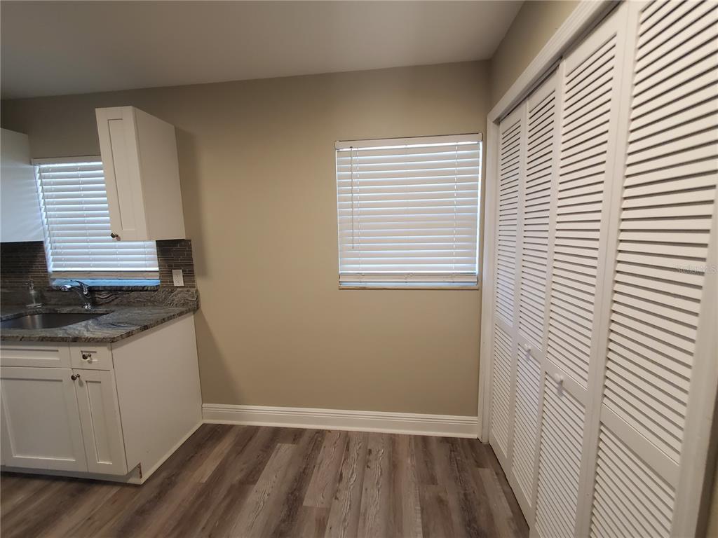 A kitchen area features white cabinets, granite countertops, a window with blinds, and louvered closet doors — 107 W CLAY AVENUE UNIT 4, BRANDON, FL