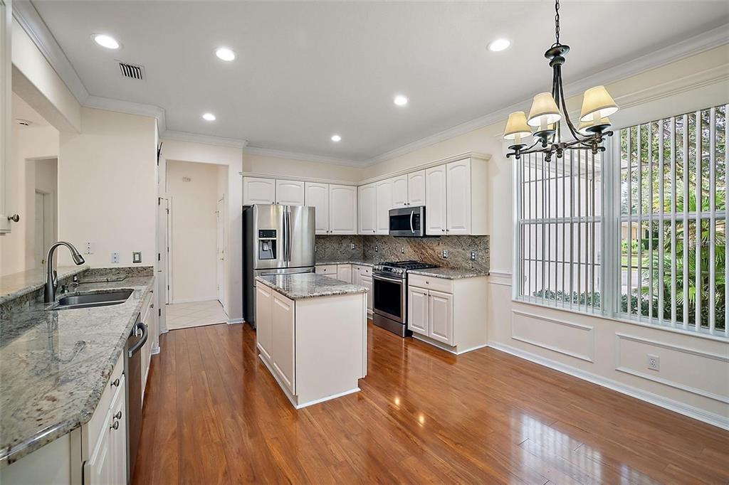 A kitchen with white cabinets, granite countertops, stainless steel appliances, and hardwood flooring — 13667 SE 91ST AVENUE, SUMMERFIELD, FL