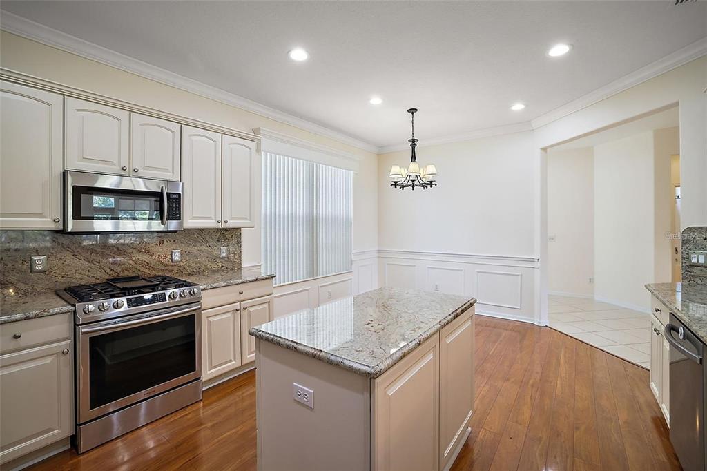 A kitchen with white cabinets, granite countertops, stainless steel appliances, and a central island — 13667 SE 91ST AVENUE, SUMMERFIELD, FL