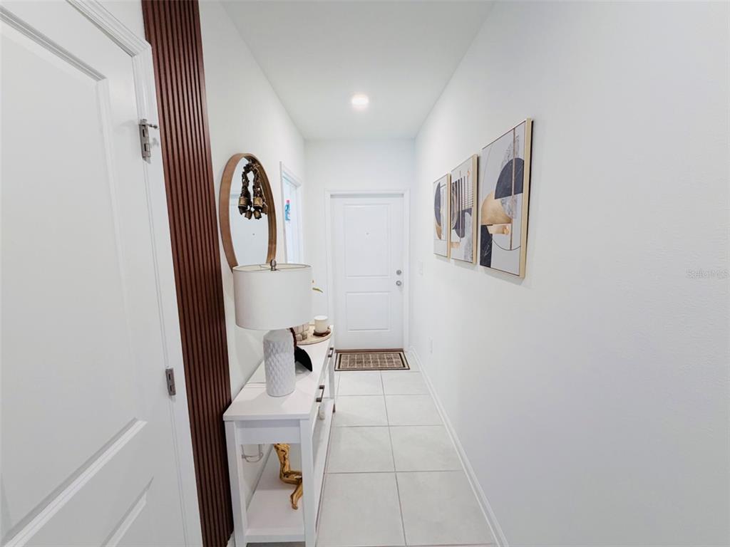 A bright entryway features white tile flooring, a console table, and wall-mounted artwork — 2715 GENTLE RAIN DRIVE, DAVENPORT, FL