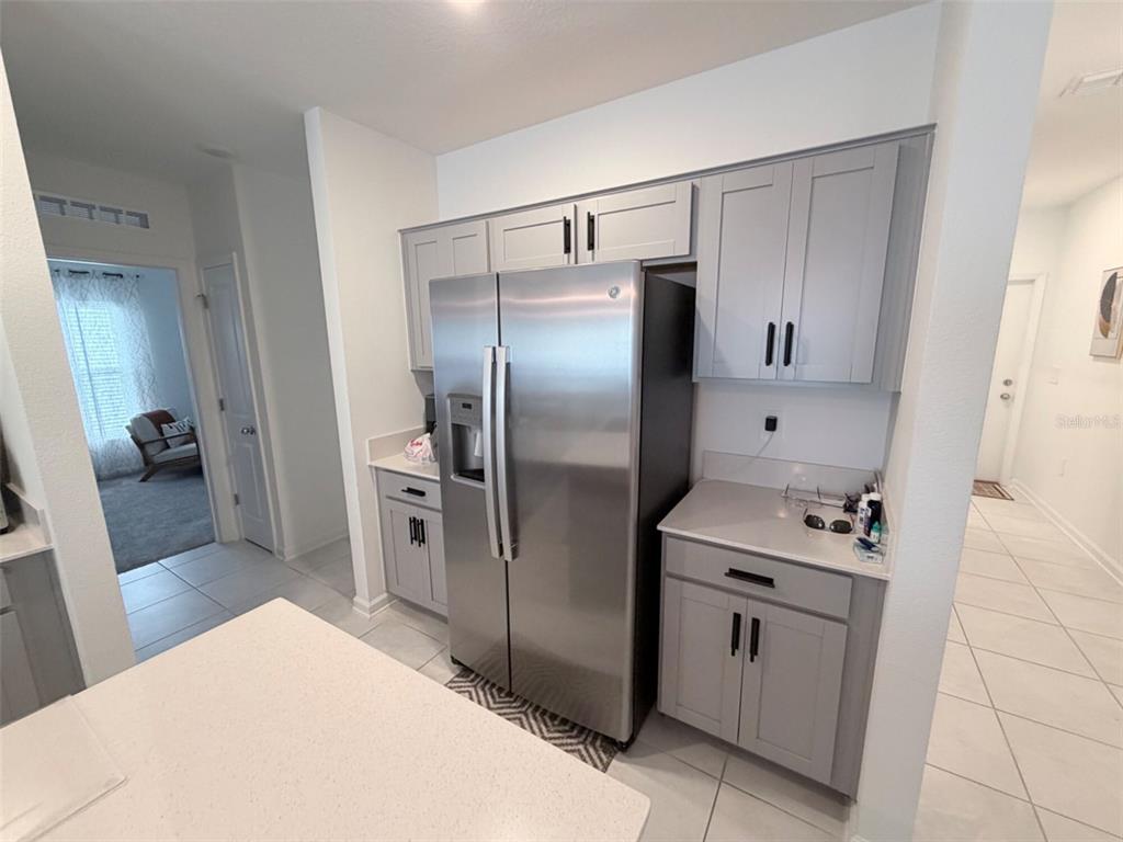 A kitchen features gray cabinets, stainless steel appliances, and light-colored countertops — 2715 GENTLE RAIN DRIVE, DAVENPORT, FL