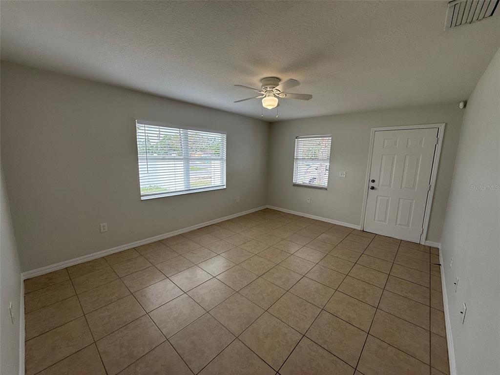 An empty room features light-colored walls, tile flooring, two windows, and a ceiling fan — 1802 MARTIN LUTHER KING AVENUE E, BRADENTON, FL