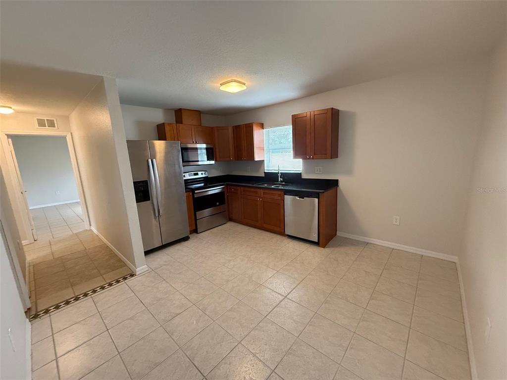 A kitchen with wood cabinets, stainless steel appliances, and light-colored tile flooring — 1802 MARTIN LUTHER KING AVENUE E, BRADENTON, FL