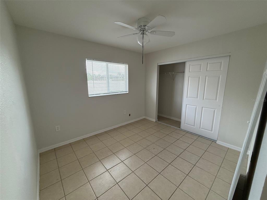 An empty bedroom features light-colored walls, a ceiling fan, a closet, and tiled flooring — 1802 MARTIN LUTHER KING AVENUE E, BRADENTON, FL