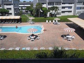 An elevated view of a swimming pool area with patio furniture and surrounding apartment buildings — 7897 Golf Cir Drive # 112, Margate FL 33063, MARGATE, FL