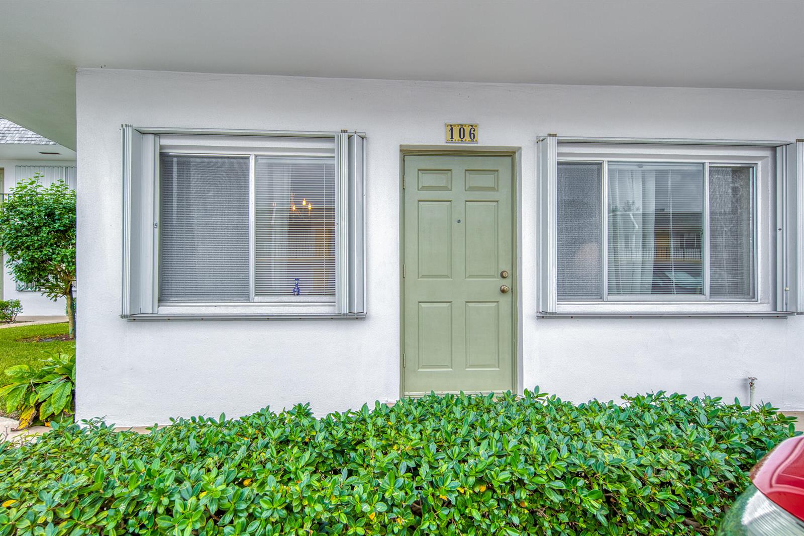 A green front door with the number 106 sits between two windows on a white building — 3040 Lake Osborne Drive # 106, FL 33461, FL