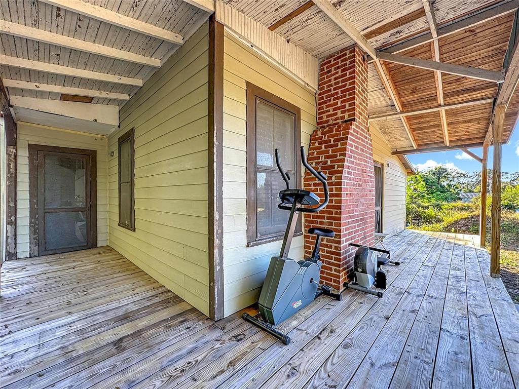 A wooden deck features a brick chimney, exercise equipment, and a covered porch area — 7717 CLARCONA OCOEE ROAD, ORLANDO, FL