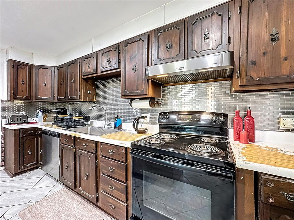 A kitchen features dark wood cabinets, a stainless steel range hood, and a tiled backsplash — 7717 CLARCONA OCOEE ROAD, ORLANDO, FL