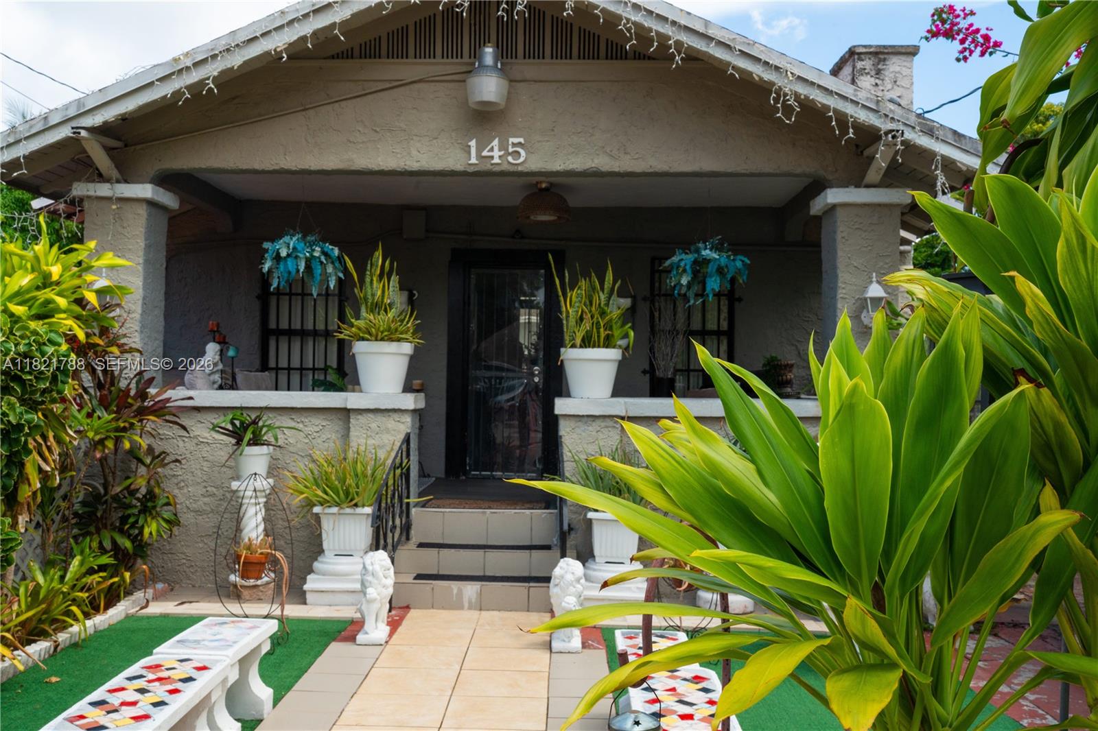 The exterior of a house features a covered porch, potted plants, and a tiled walkway — 145 NW 31st St, Miami FL 33127, MIAMI, FL