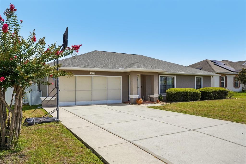 A single-story house with a concrete driveway, a basketball hoop, and a landscaped front yard — 5179 SE 92ND STREET, OCALA, FL