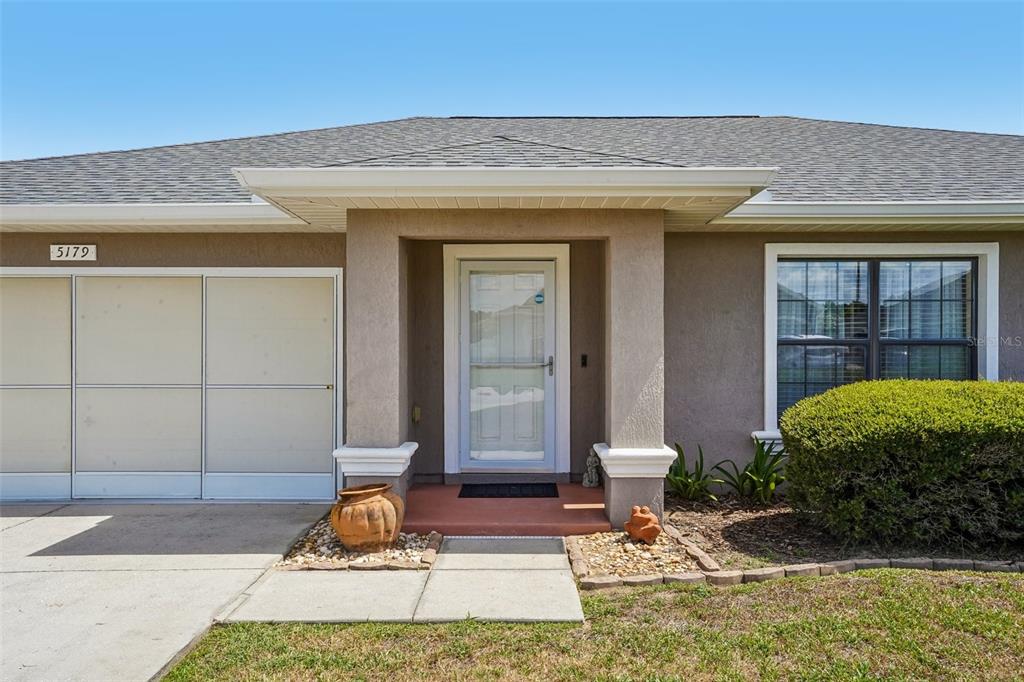 The exterior of a single-story house features a garage, a covered entryway, and a window — 5179 SE 92ND STREET, OCALA, FL