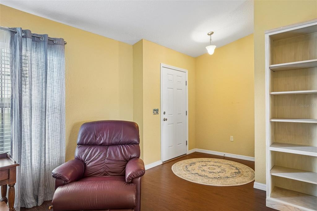 A room with yellow walls, a maroon leather recliner, a white door, and a bookshelf — 5179 SE 92ND STREET, OCALA, FL