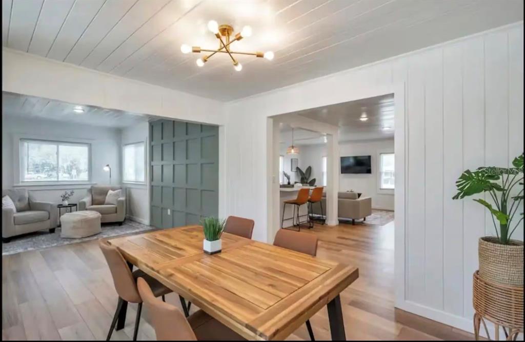 A dining room with a wood table, modern light fixture, and views into adjacent living spaces — 1507 10TH AVENUE W, PALMETTO, FL