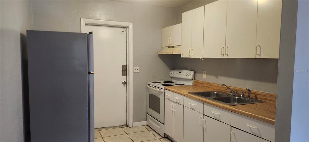 A kitchen features white cabinets, a stainless steel refrigerator, an electric stove, and wood-look countertops — 8501 N MULBERRY STREET UNIT B, TAMPA, FL