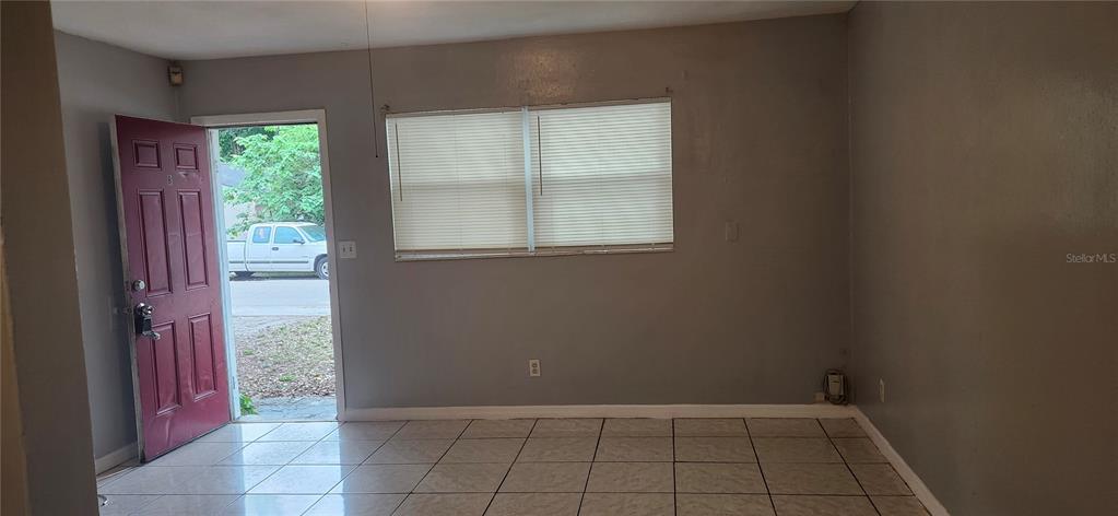 A room with light-colored tile flooring, gray walls, a window with blinds, and an open door — 8501 N MULBERRY STREET UNIT B, TAMPA, FL