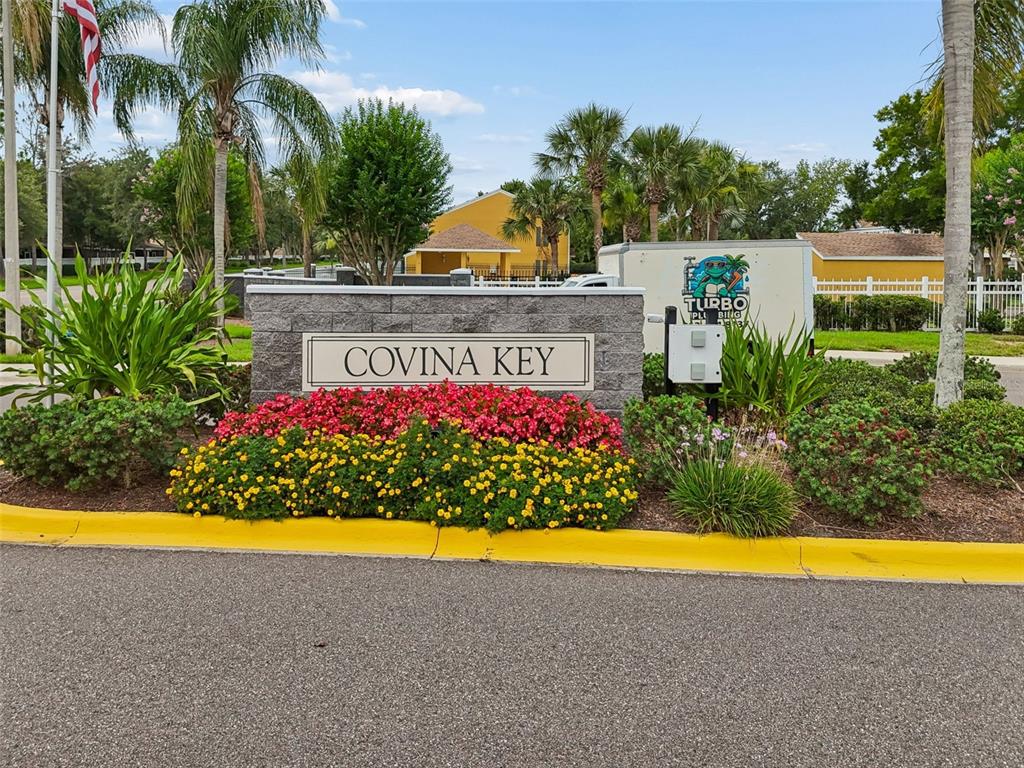 A stone monument sign for Covina Key sits in front of colorful flowers and landscaping — 30005 GRANDA HILLS COURT, WESLEY CHAPEL, FL