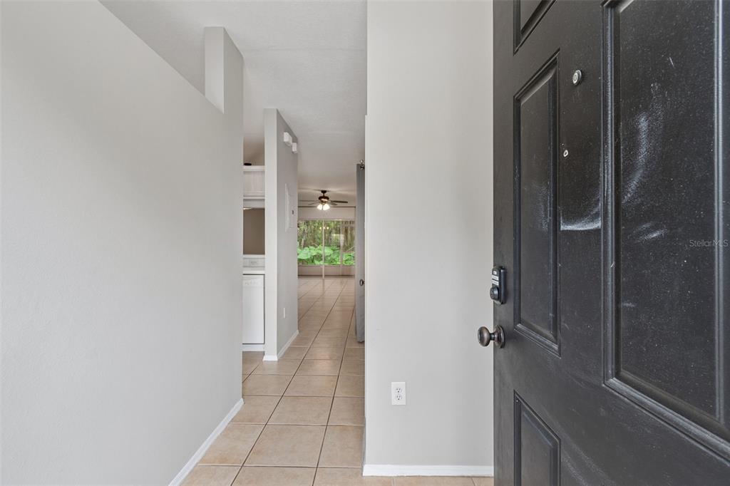 A view from an open black front door into a tiled hallway leading to living space — 30005 GRANDA HILLS COURT, WESLEY CHAPEL, FL