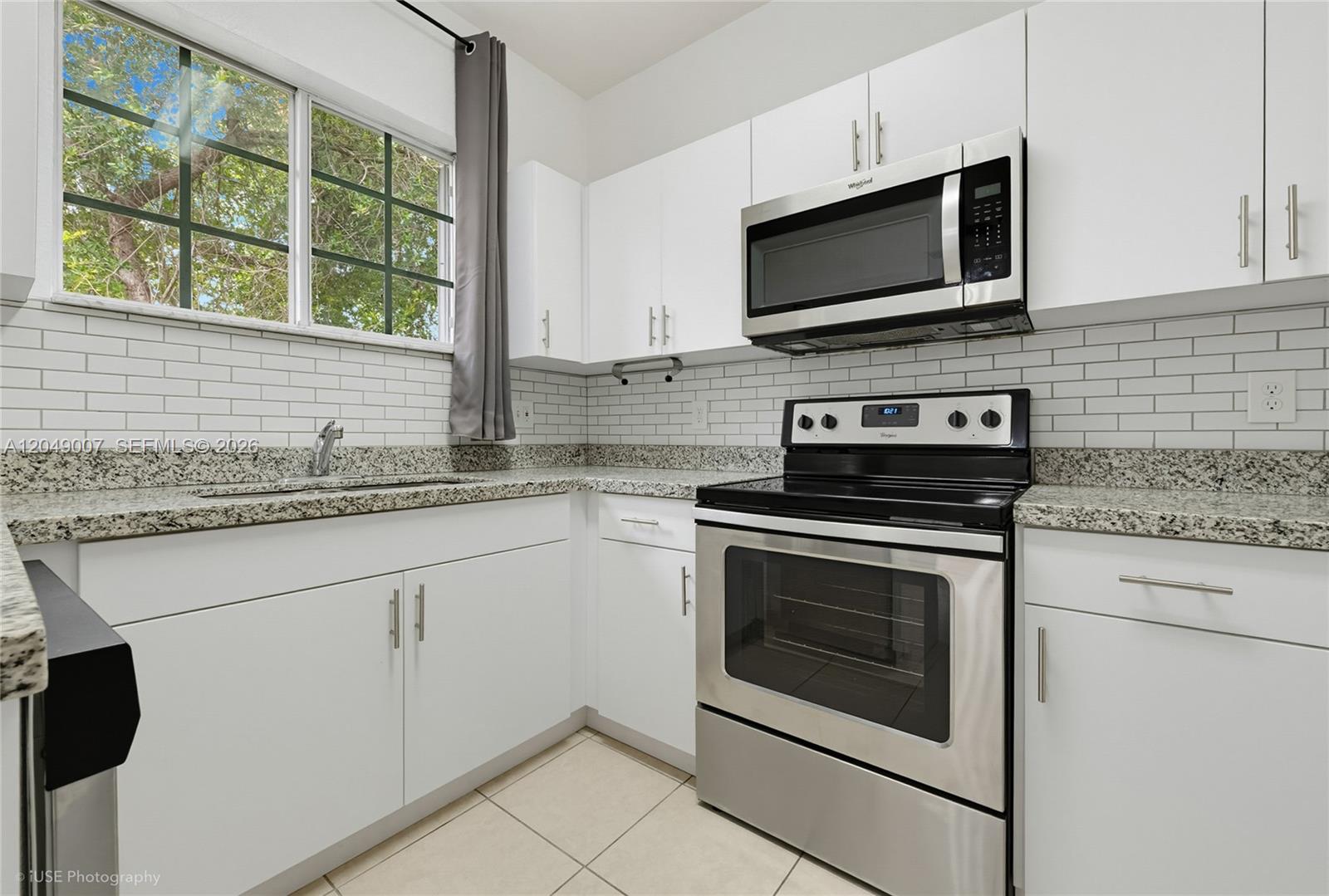 A kitchen features white cabinets, stainless steel appliances, granite countertops, and a subway tile backsplash — 2630 NE 3rd Dr # 204, Homestead FL 33033, HOMESTEAD, FL