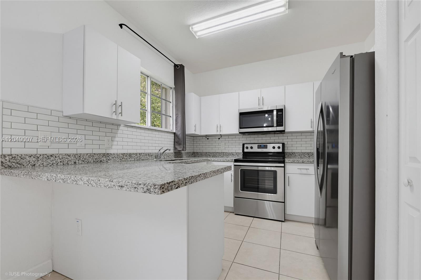 A kitchen features white cabinets, granite countertops, stainless steel appliances, and a subway tile backsplash — 2630 NE 3rd Dr # 204, Homestead FL 33033, HOMESTEAD, FL