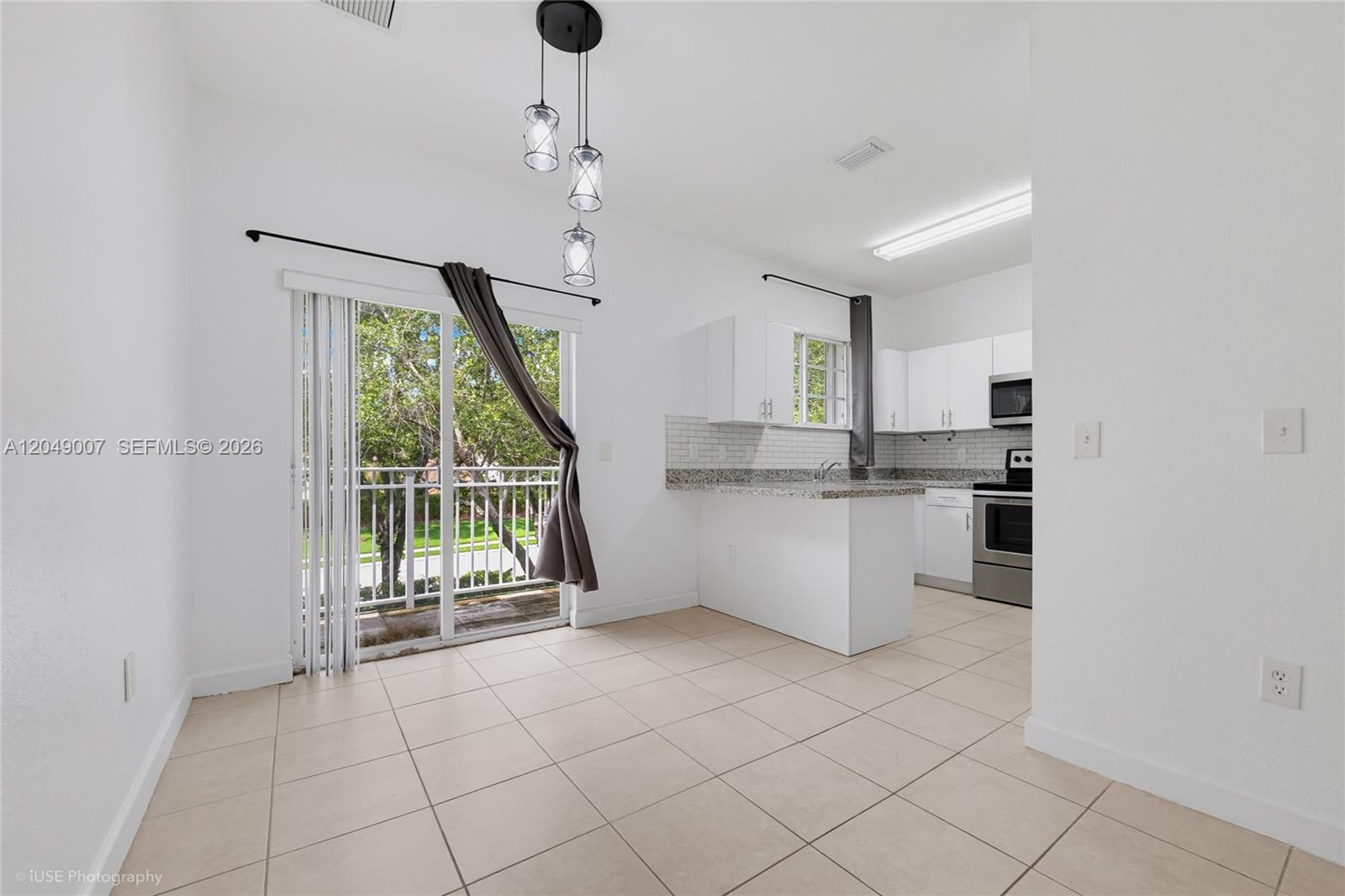 A kitchen with white cabinets and a dining area featuring a sliding glass door — 2630 NE 3rd Dr # 204, Homestead FL 33033, HOMESTEAD, FL