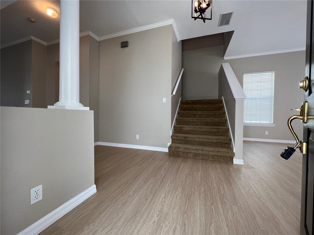An entryway features light wood-look flooring, a carpeted staircase, and a white support column — 502 GREENBRIER AVENUE, KISSIMMEE, FL
