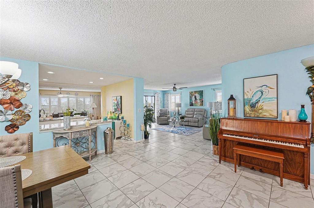 A spacious living and dining area features light blue walls, tile flooring, and a piano — 8198 TERRACE GARDEN DRIVE N UNIT 411, ST PETERSBURG, FL