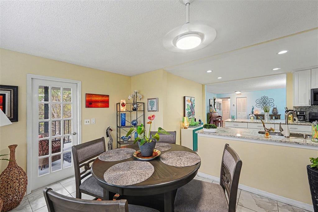 A dining area with a round table, chairs, and a view into an open kitchen — 8198 TERRACE GARDEN DRIVE N UNIT 411, ST PETERSBURG, FL