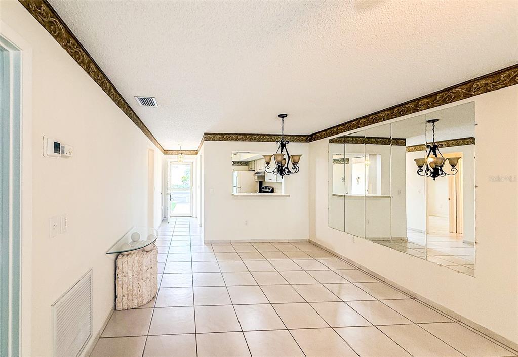 A dining area features tiled floors, a mirrored wall, and a chandelier under crown molding — 2604 WOODGATE LANE UNIT J6, SARASOTA, FL