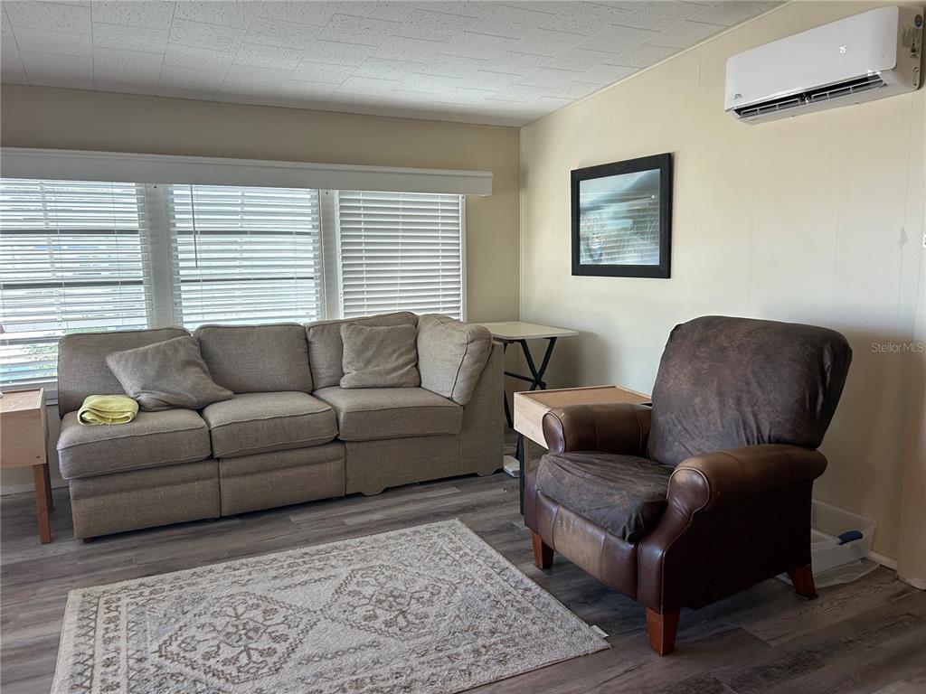 A living room features a beige sofa, a brown leather armchair, and a wall-mounted air conditioner — 5325 BOCA RATON AVENUE, SARASOTA, FL