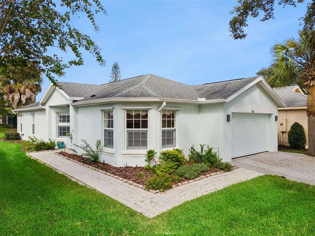 A light-colored single-story house with a paved walkway, a garage, and a landscaped front yard — 205 BELL TOWER CROSSING WEST, POINCIANA, FL