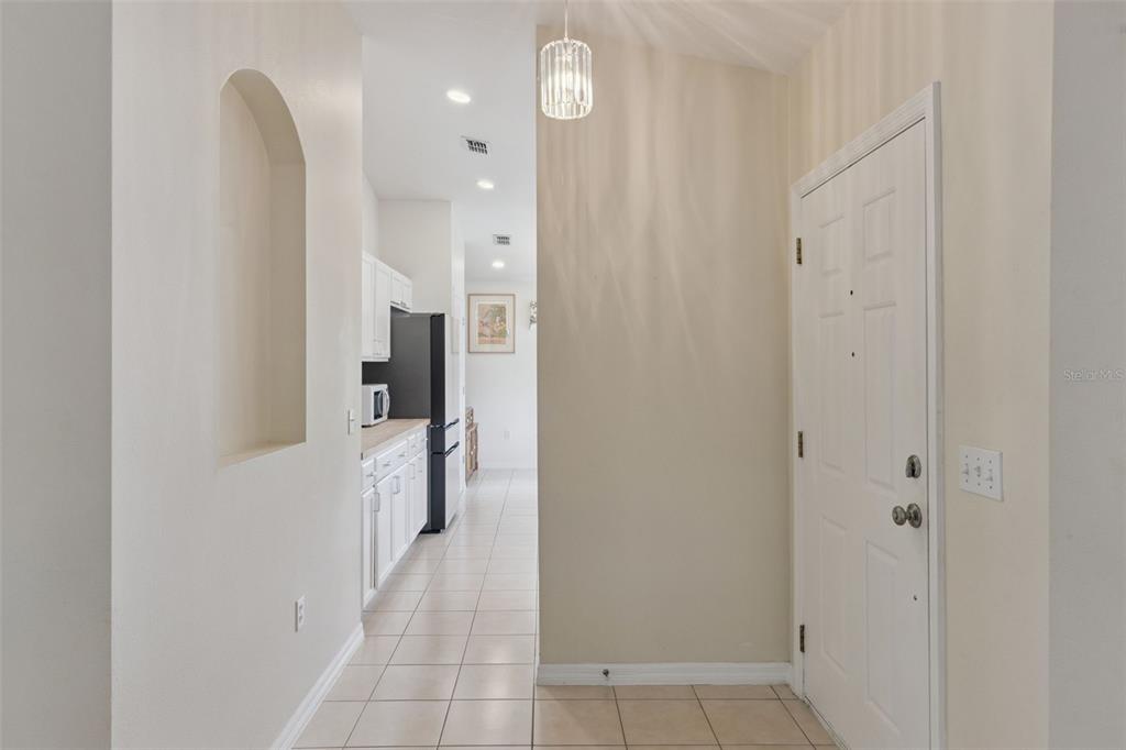 A tiled entryway leads to a kitchen with white cabinets and a black refrigerator — 205 BELL TOWER CROSSING WEST, POINCIANA, FL