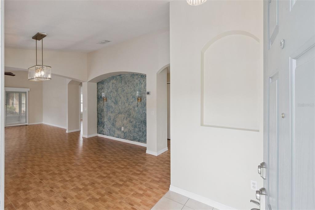 An entryway leads into a living area with tile flooring and a blue accent wall — 205 BELL TOWER CROSSING WEST, POINCIANA, FL