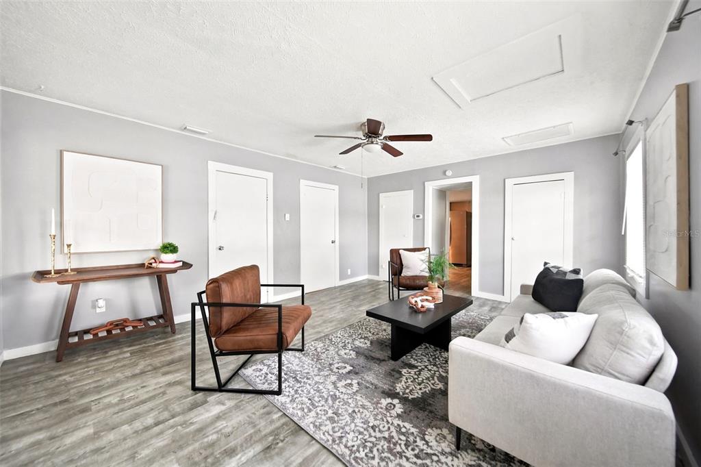 A living room features gray walls, wood-look flooring, a ceiling fan, and modern furniture — 109 E BASS STREET, KISSIMMEE, FL