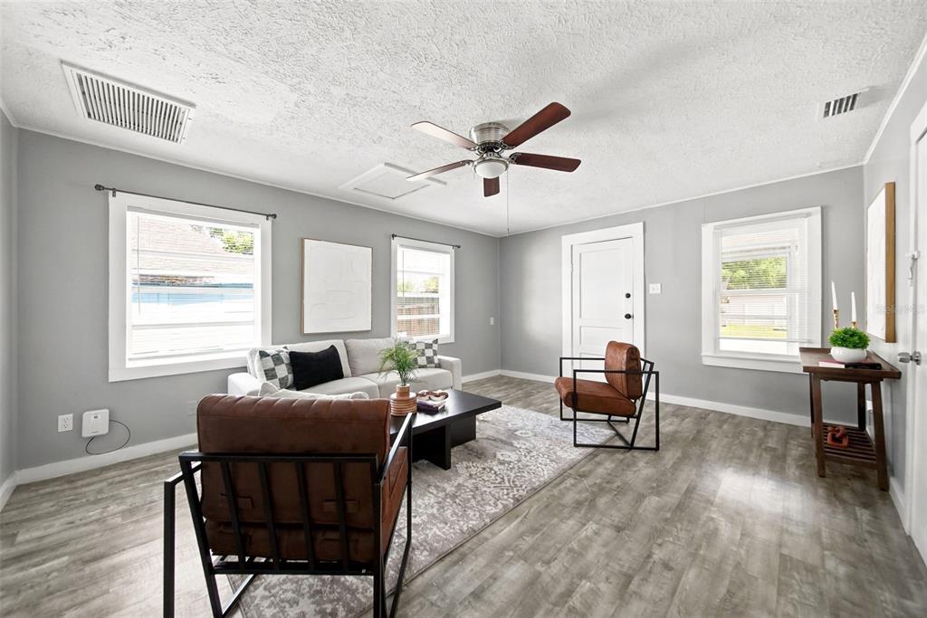 A living room features gray walls, wood-look flooring, a ceiling fan, and modern furniture — 109 E BASS STREET, KISSIMMEE, FL
