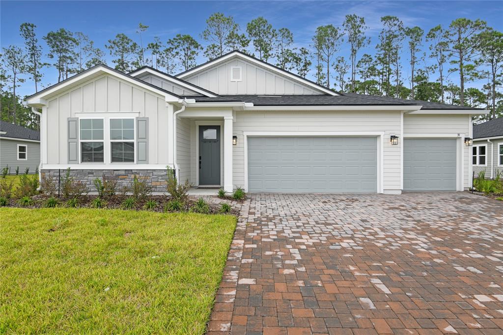 A single-story house features white siding, a stone base, and a paved driveway — 39 PONCE PRESERVE DRIVE, PALM COAST, FL