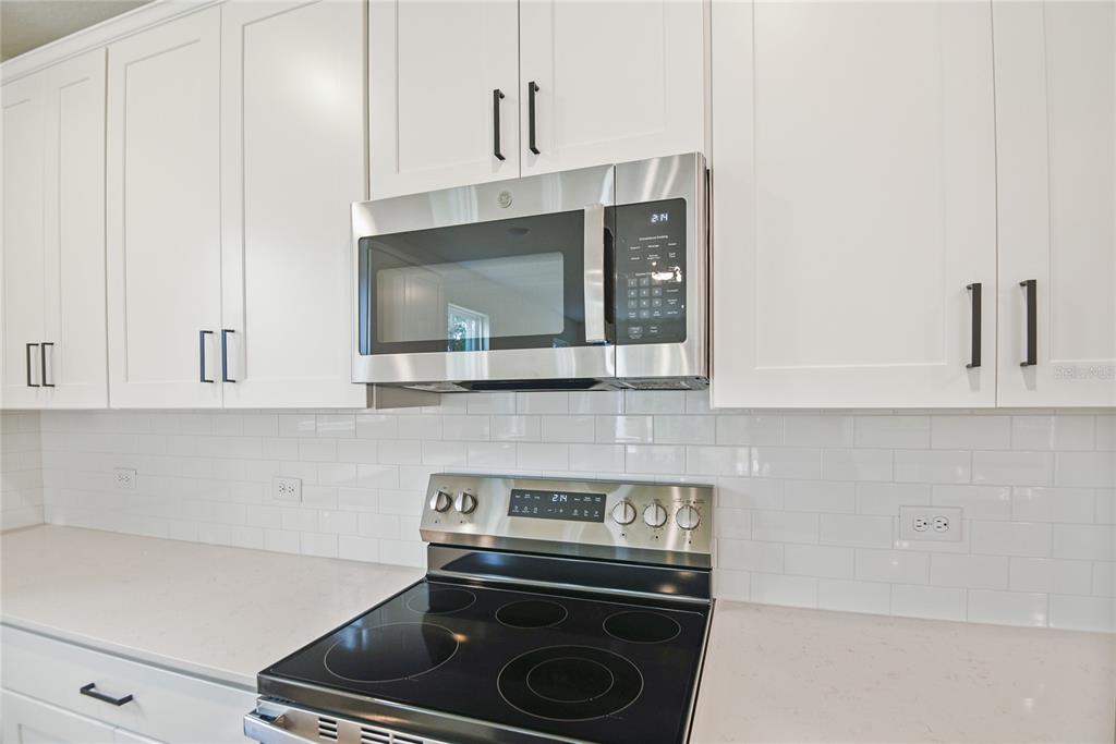 A kitchen features white cabinets, a stainless steel microwave, and a black electric range — 39 PONCE PRESERVE DRIVE, PALM COAST, FL