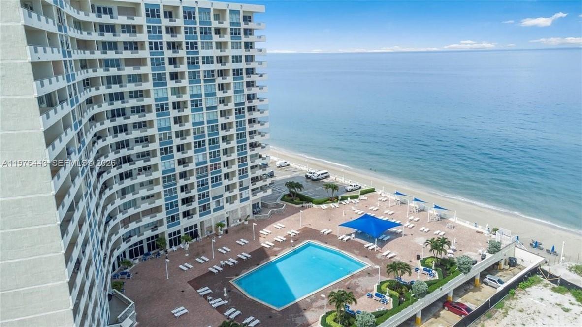 An aerial view shows a high-rise beachfront condominium building with an outdoor pool and deck — 3180 S Ocean Dr # 1018, Hallandale Beach FL 33009, HALLANDALE BEACH, FL