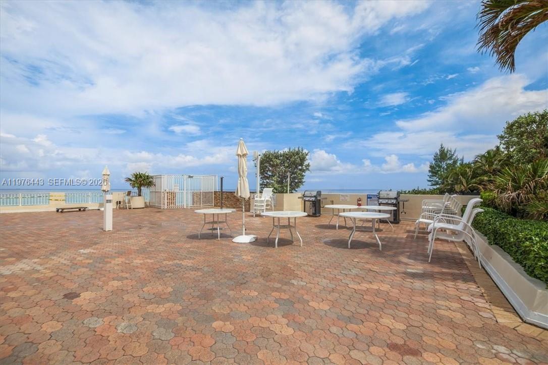 An outdoor patio features paved flooring, several tables, chairs, and a grill overlooking the ocean — 3180 S Ocean Dr # 1018, Hallandale Beach FL 33009, HALLANDALE BEACH, FL