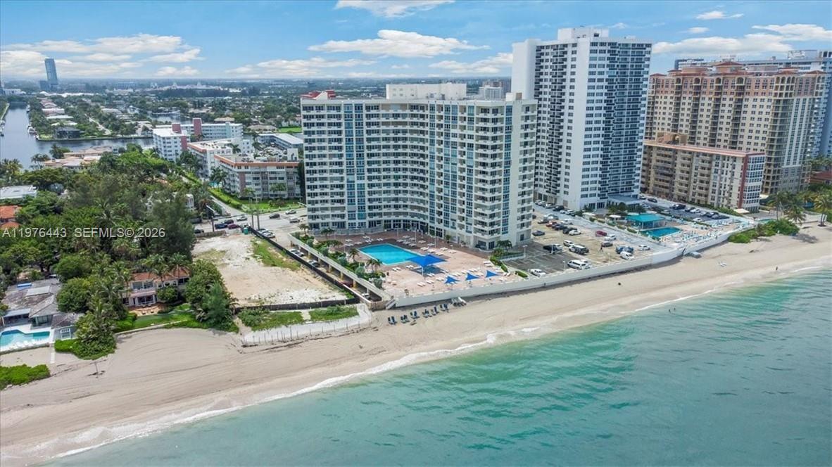An aerial view shows a high-rise condominium building situated directly on a sandy beach — 3180 S Ocean Dr # 1018, Hallandale Beach FL 33009, HALLANDALE BEACH, FL