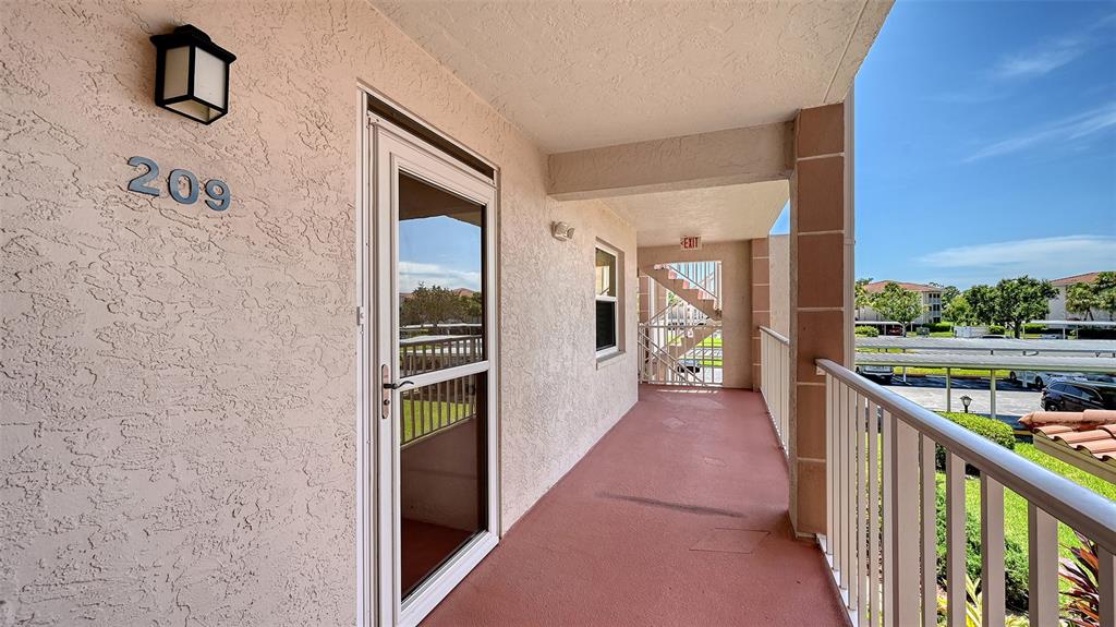 An exterior balcony with a white door, a light fixture, and a metal railing — 6505 STONE RIVER ROAD UNIT 209, BRADENTON, FL