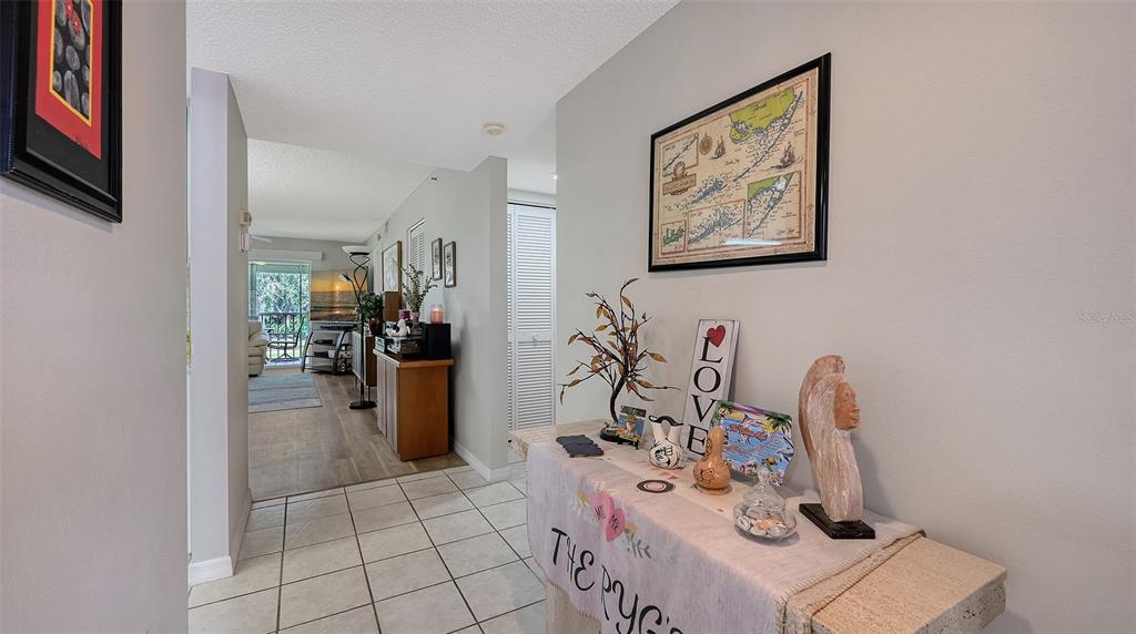 A tiled entryway features a console table with decor and a view into the living area — 6505 STONE RIVER ROAD UNIT 209, BRADENTON, FL