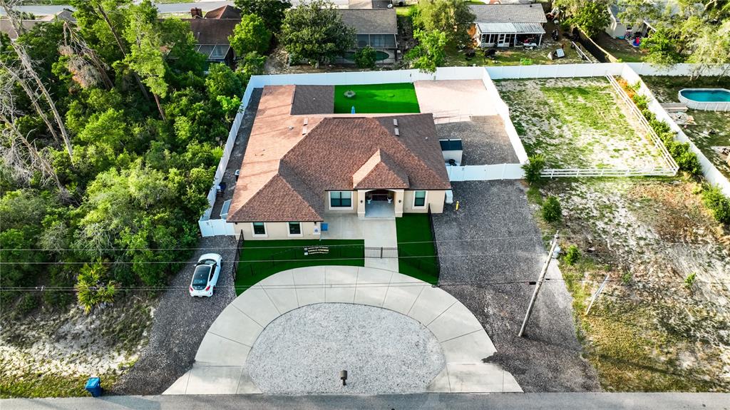 An aerial view shows a house with a brown roof, circular driveway, and fenced yard — 13031 PARTRIDGE STREET, SPRING HILL, FL